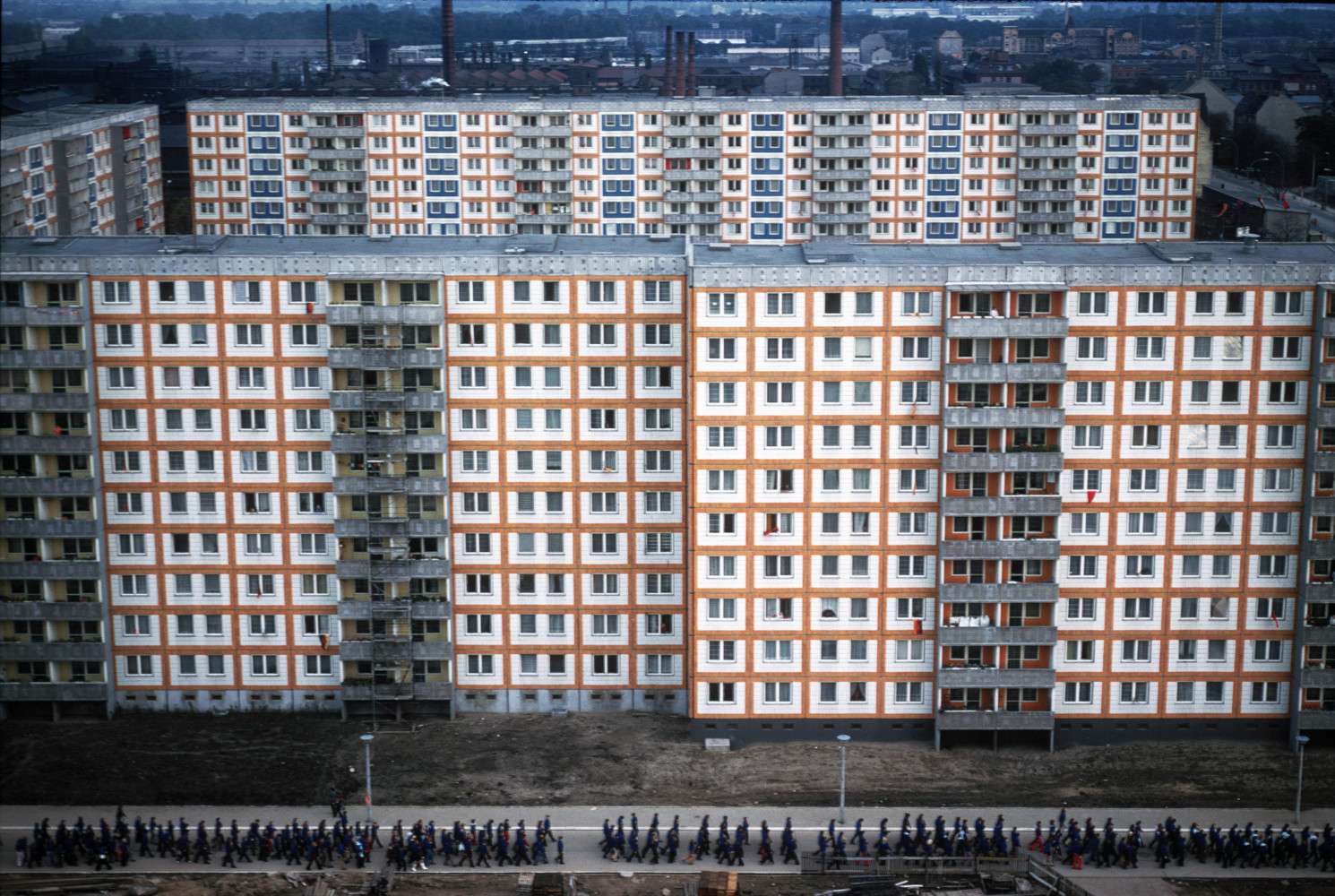 Thomas Hoepker, Ost-Berlin, Ostdeutschland, 1. Mai 1975, ein Demonstrationszug zum Maifeiertag führt am neuen Arbeiterwohnungsbau Plattenbau im Stadtteil Weißensee vorbei